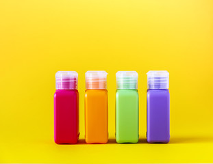 Colorful plastic bottles for skincare products or different purposes on yellow background