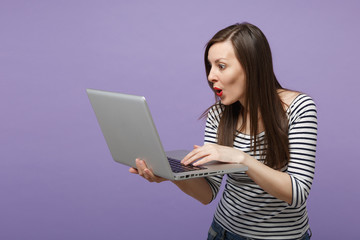 Naklejka premium Young brunette woman girl in casual striped clothes posing isolated on violet purple background studio portrait. People sincere emotions lifestyle concept. Mock up copy space. Hold tablet pc computer.