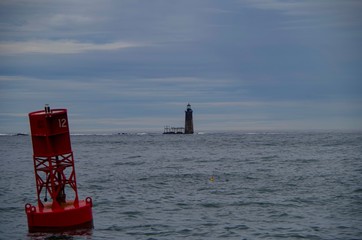 Ram Island Ledge Light Station lighthouse on the sea with red buoy