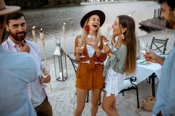 Young friends having fun, hanging out together with wine glasses during a festive dinner on the...