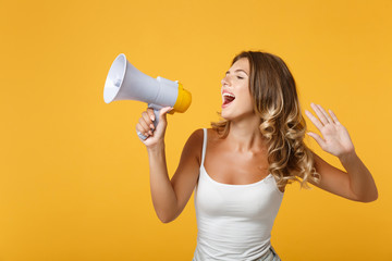 Young woman girl in light casual clothes posing isolated on yellow orange background, studio portrait. People sincere emotions lifestyle concept. Mock up copy space. Scream in megaphone, showing palm.