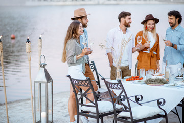 Young friends hanging out together, standing with wine glasses near the beautifully decorated...