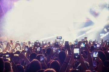 People taking photographs with touch smart phone during a music entertainment public concert