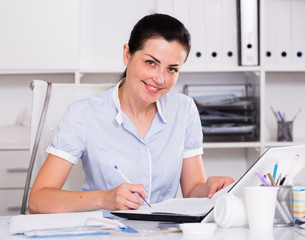 smiling businesswoman filling up documents