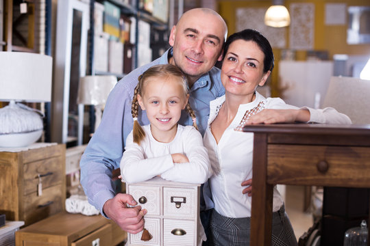 Happy family with small daughter in furniture showroom