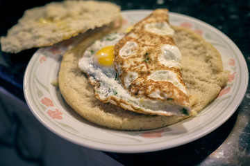 arepa with a fried egg topping it on a white plate