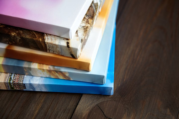 Photo canvas prints on wooden background. Stacked colorful photographs with gallery wrap method of canvas stretching on stretcher bar, lateral side