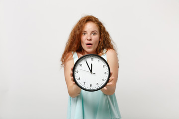 Young shocked excited amazed redhead woman girl in casual light clothes posing isolated on white wall background, studio portrait. People lifestyle concept. Mock up copy space. Holding round clock.
