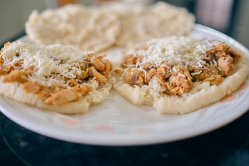 Arepas with shredded chicken, butter and cheese. Hot, you can see the steam and the butter melting. Served on a white plate.