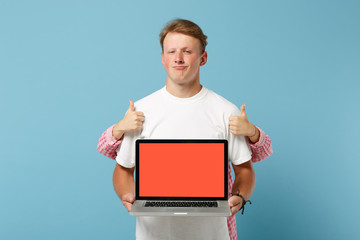 Young couple two friends guy girl in white pink t-shirts posing isolated on blue background. People lifestyle concept. Mock up copy space. Showing thumbs up, hold laptop pc computer with empty screen.