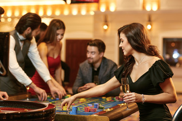 A young woman sitting at table roulette playing poker at a casino.
