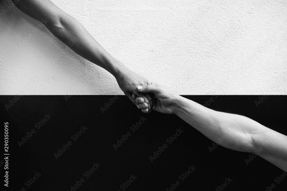 Wall mural two hands holding each other in a black and white background