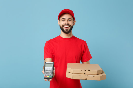 Delivery man in red workwear giving food order pizza boxes isolated on blue background, studio portrait. Professional male employee in cap t-shirt print courier. Service concept. Mock up copy space.