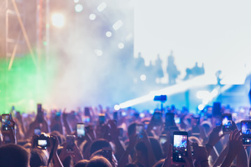 People taking photographs with touch smart phone during a music entertainment public concert