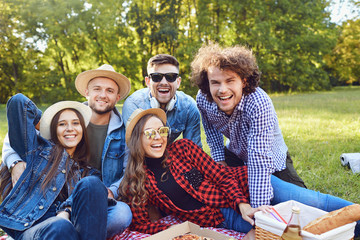 Obraz premium A group of people sitting on the grass on a picnic.