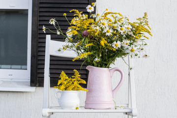 Bouquet in jar on background of house white wall