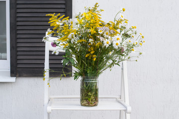 Bouquet in jar on background of house white wall