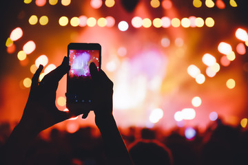 People taking photographs with touch smart phone during a music entertainment public concert