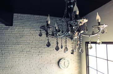 crystal chandelier and white watch on white brick wall behind , copy space