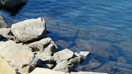 Wasser mit kleinen Wellen und Steinufer