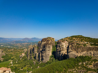 Fototapeta na wymiar Aerial view of a mountain range. View of the cliffs of Meteora and the monasteries of Meteora. Many ancient Orthodox monasteries summer. Photo from drone. Kalampaka town, Greece.