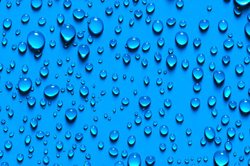 Close up Beaded glistening water droplets on blue surface