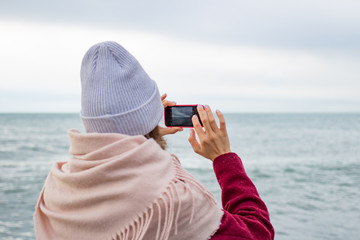 Girl photographs the sea on a smartphone