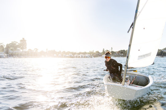 Teenage boy sailing an optimist dinghy