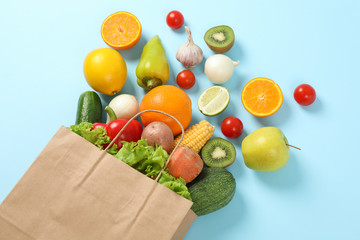 Paper bag, vegetables and fruits on blue background, space for text