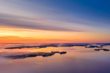 Fototapeta na wymiar Long Exposure of Sunrise at the Paijanne lake. Beautiful scape with sunrise sky,fog, pine forest and water. Lake Paijanne, Finland.