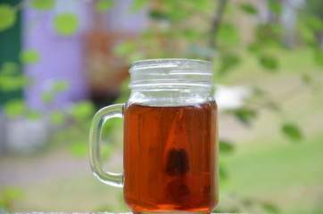 Cup of tea on nature background in a jar of maison with a tea bag
