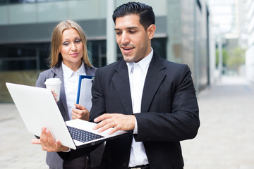 Two office workers are examining project on a laptop