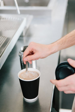 Close up of a mans hands making a coffee to take away in a cafe