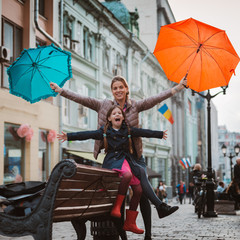 Little girl 6 years old child with an umbrella in rubber boots having fun with her mother on a...