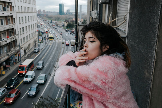 Portrait of a young female model with dreadlock smoking cigarette on the balcony