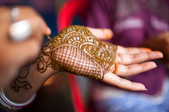 woman applying mehendi in hand in a hindu marriage occassion