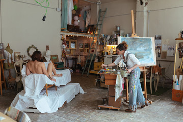 Artist woman drawing a model in her studio.