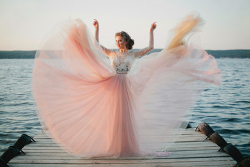 Beautiful model posing in wedding dress on a pier
