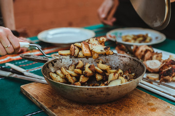 Frying pan with fried potatoes lies on the table in the sun