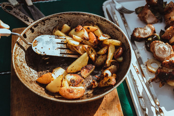 Frying pan with fried potatoes lies on the table in the sun