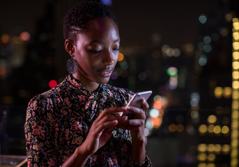 Woman checking her smart phone on a rooftop bar