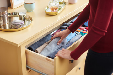 Woman decluttering clothes in drawer.