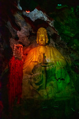 Beautiful illuminated multicolored Big Buddha in Danzhou Stone Flower Caves, Geopark next to Haikou, Hainan, China