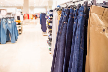 Trousers hang on rails in modern clothes shop