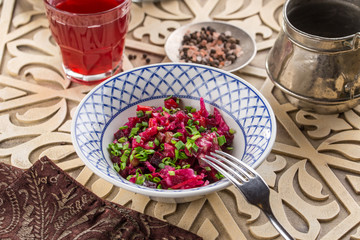 beetroot salad vinaigrette with green onion on plate on oriental wooden background