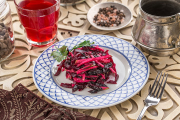 beetroot salad with apple on plate and glass of red drink on oriental wooden background