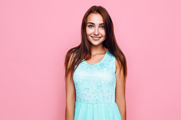 young girl, in a bright dress, smiling and posing on a pink background