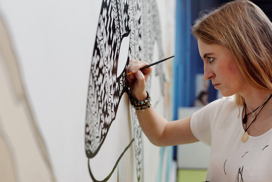 Woman painting whale on wall