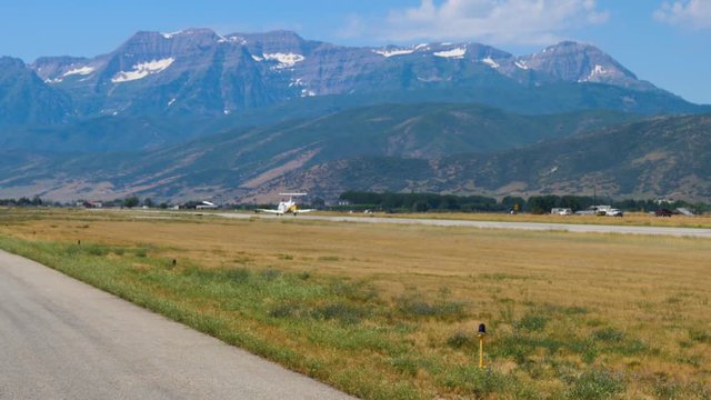 HEBER, UT, UNITED STATES, SEPTEMBER 7, 2019: White colored business jet is driving on the runway for take off. High mountains of Heber Valley mountains in the background and 8 seats white business jet