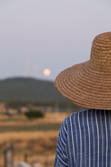 the villager woman wearing wicker hat hold the moon.